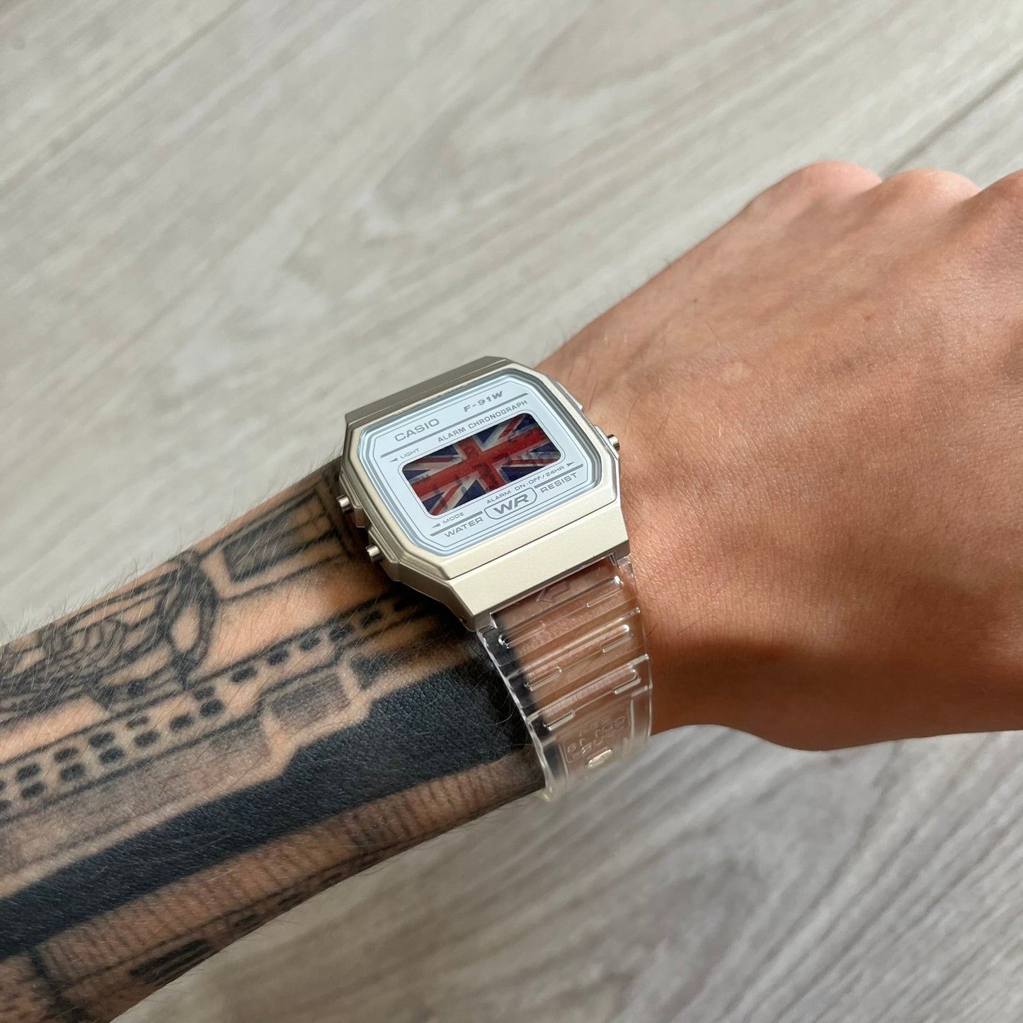 Person wearing a watch with a Union Jack design on a wooden surface