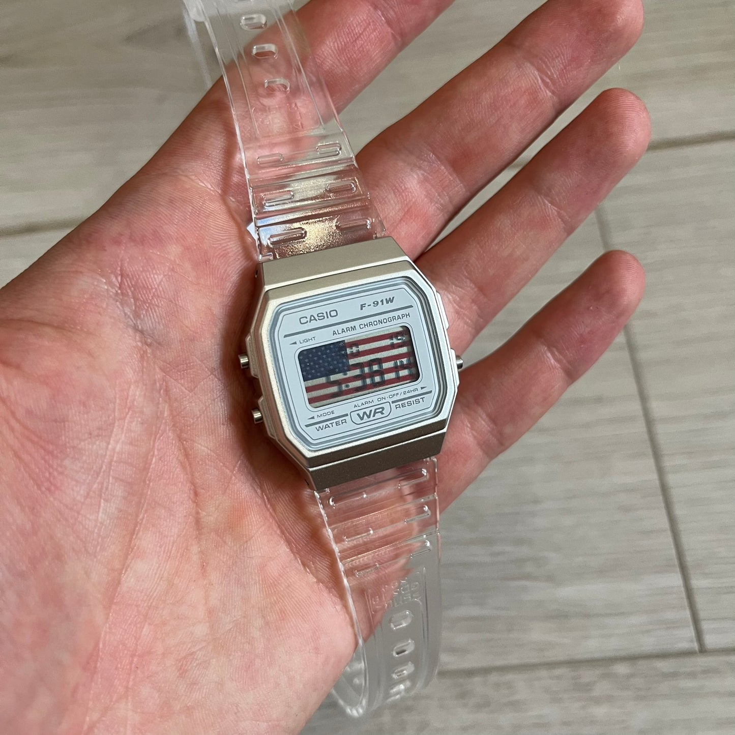Casio watch with American flag display on a hand against a tiled floor background