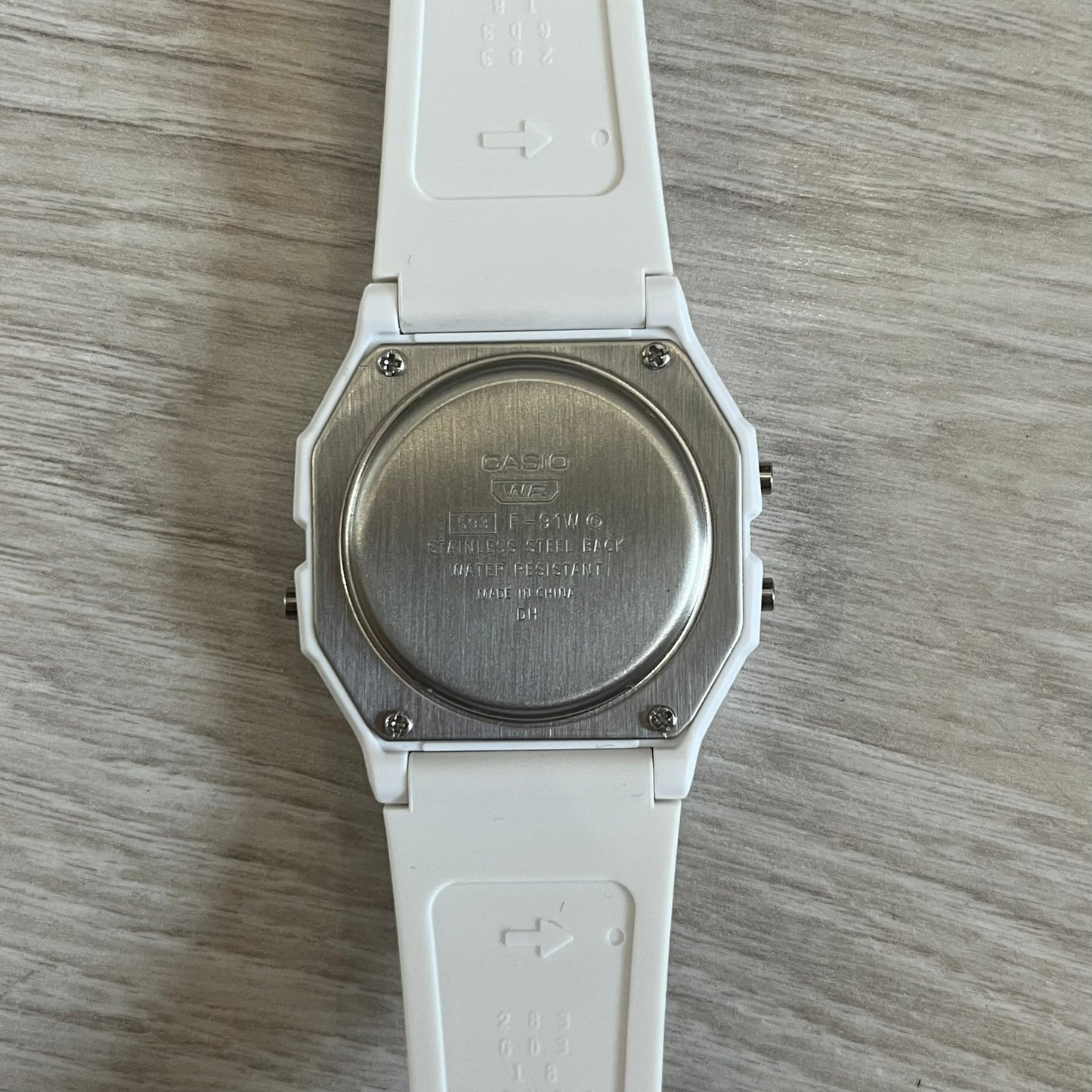 Back view of a white Casio watch on a wooden surface