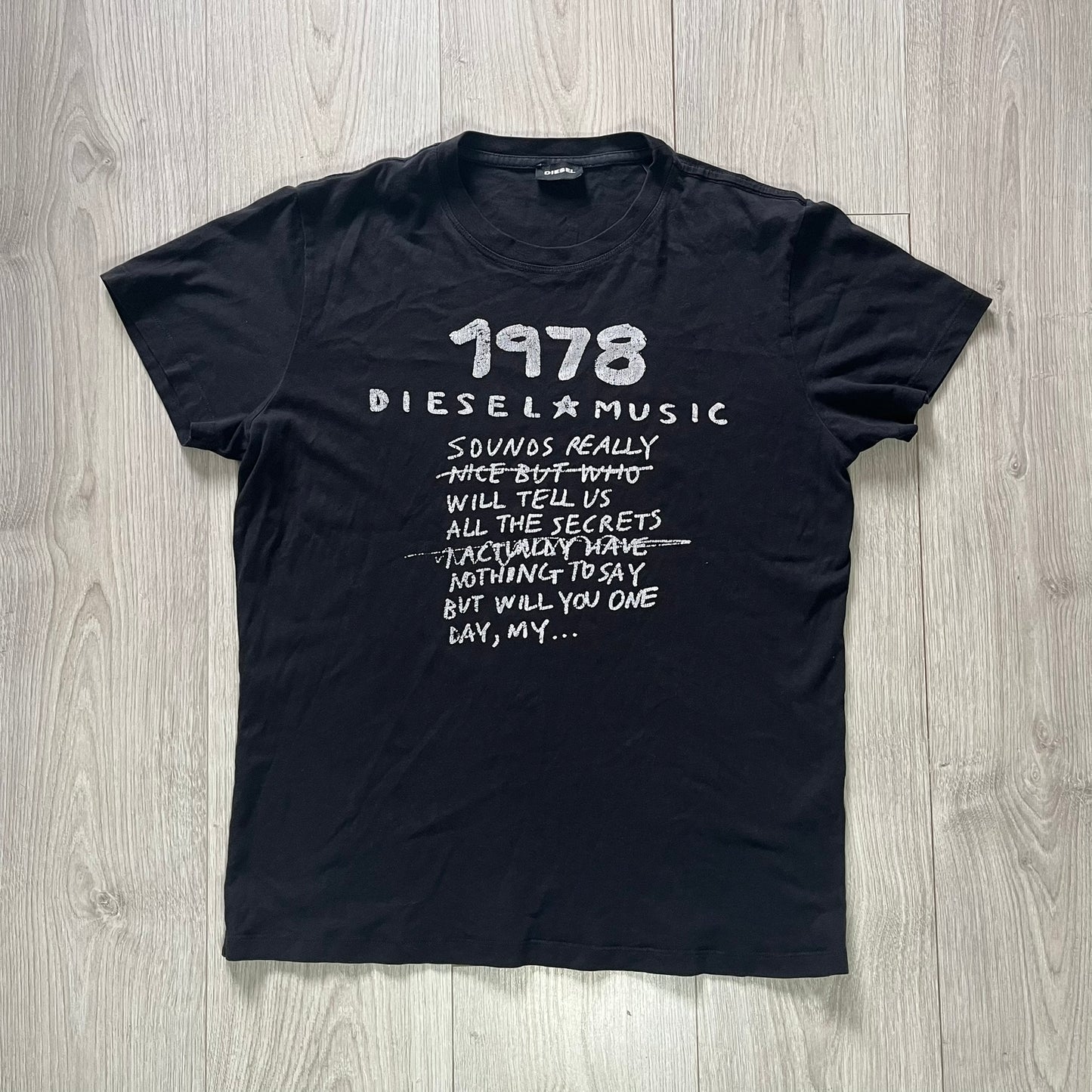Black t-shirt with white text on a wooden surface