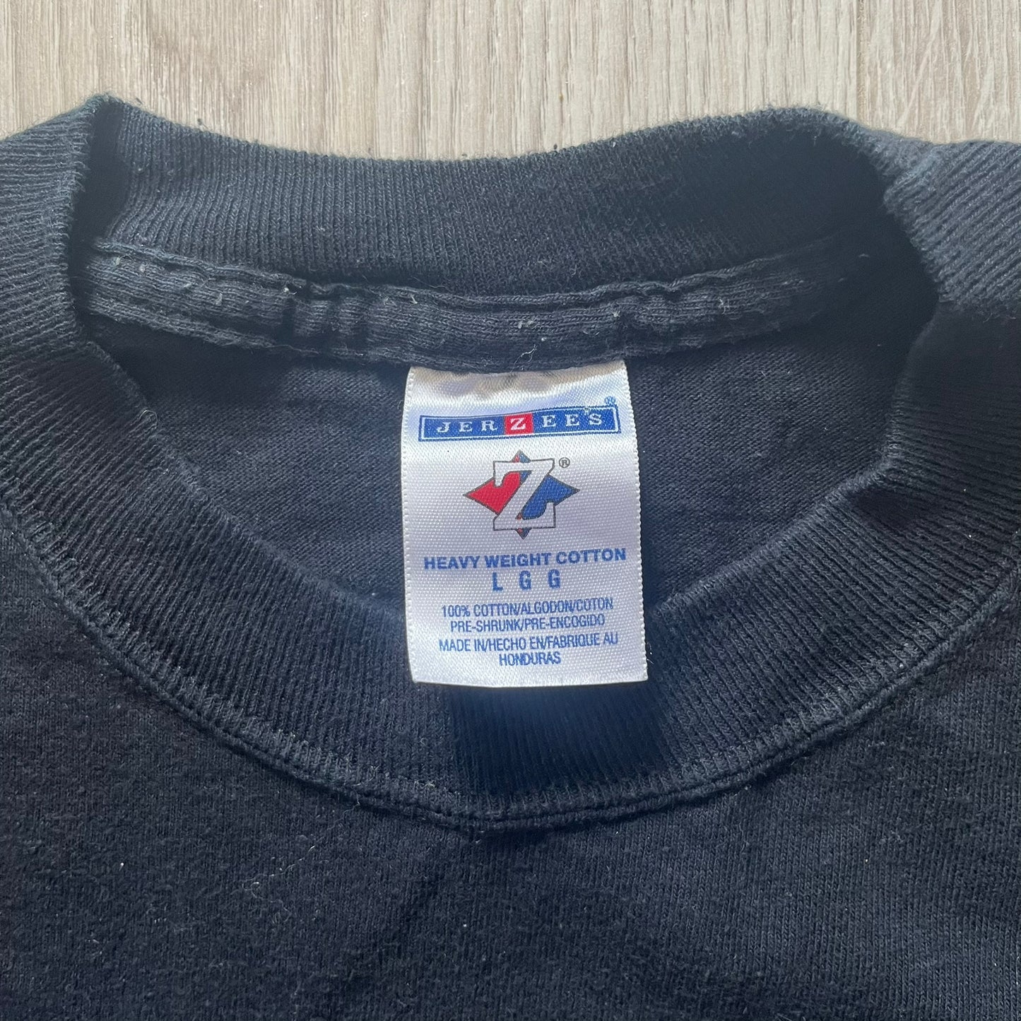 Close-up of a navy blue shirt with a Jerzees label on a wooden surface