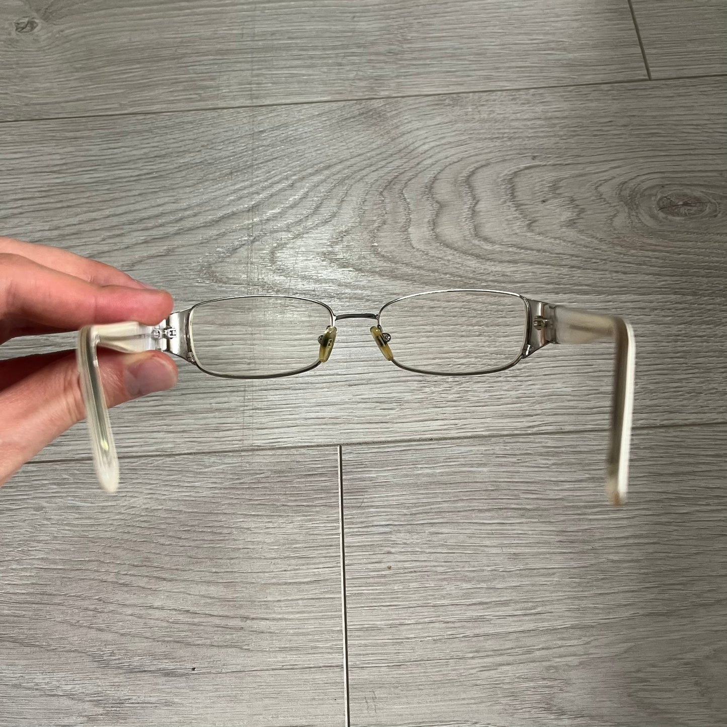 Eyeglasses held by a hand on a wooden floor background