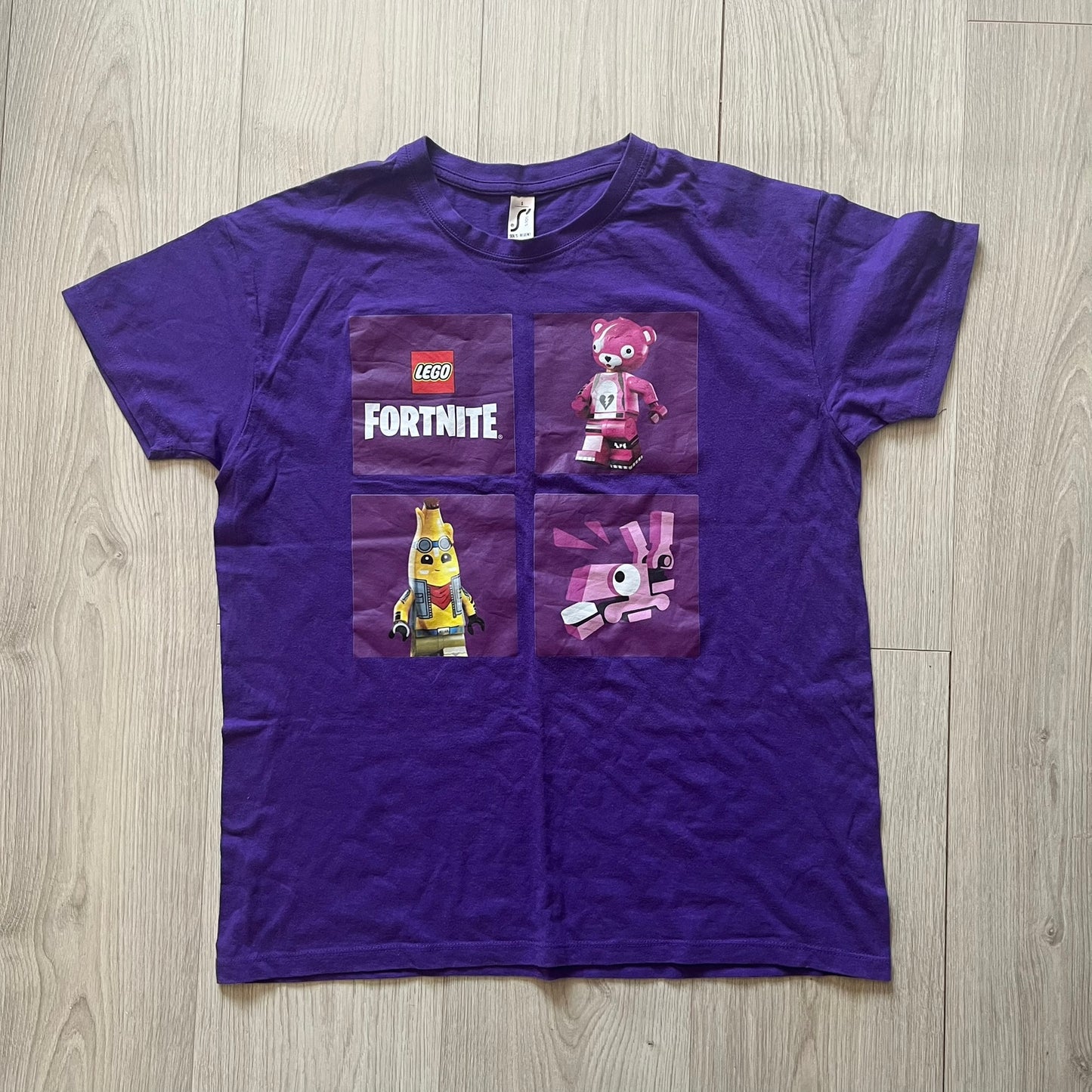 Purple t-shirt with LEGO Fortnite characters on a wooden surface