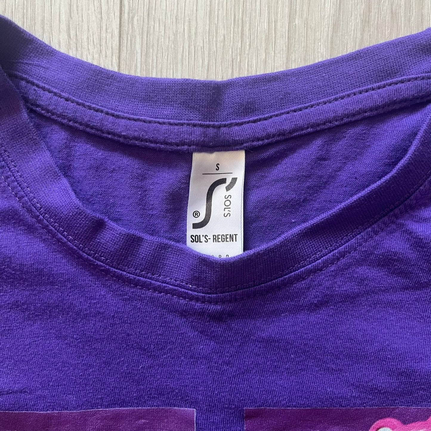Close-up of a purple garment with a visible label on a wooden surface