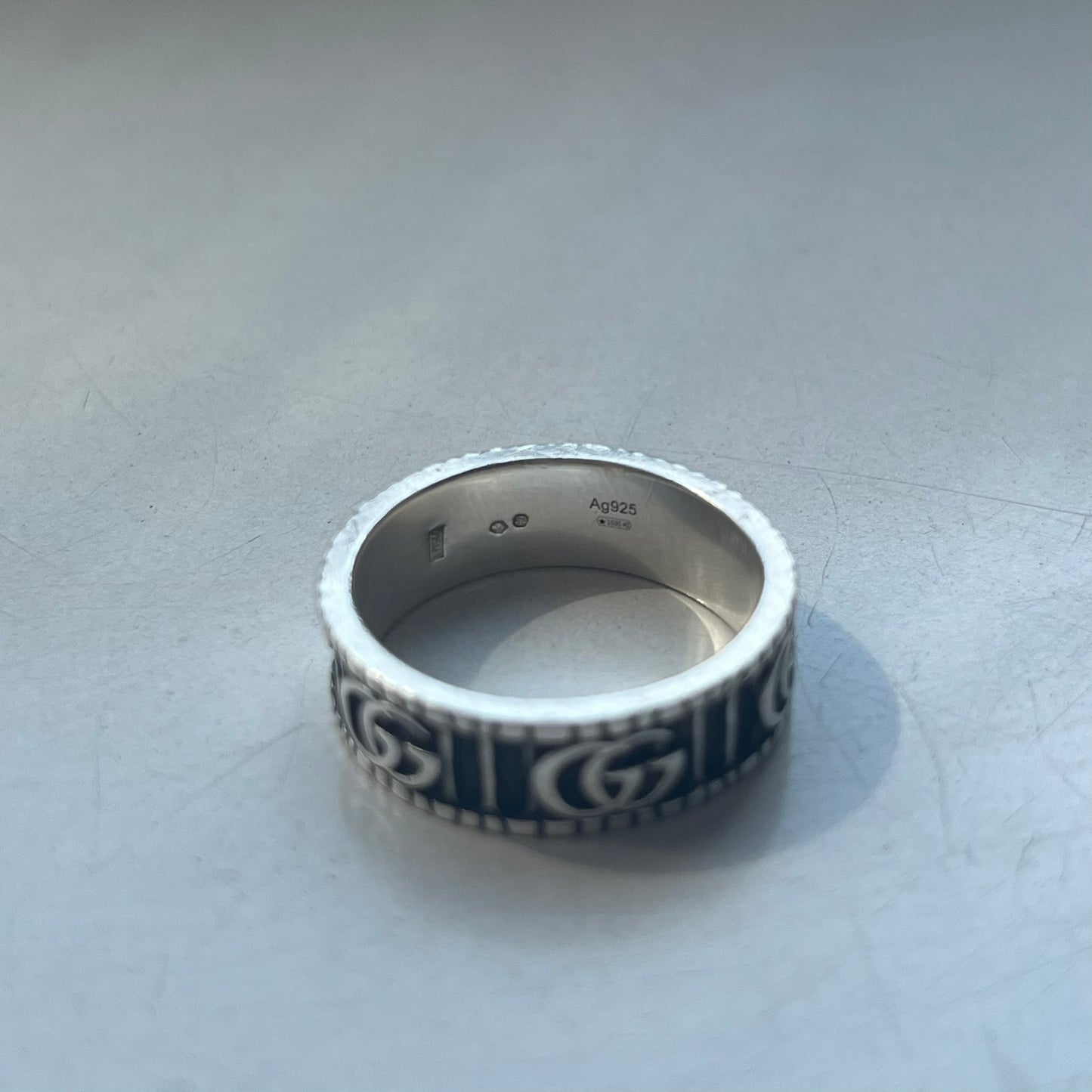 Silver ring with decorative design on a light gray surface