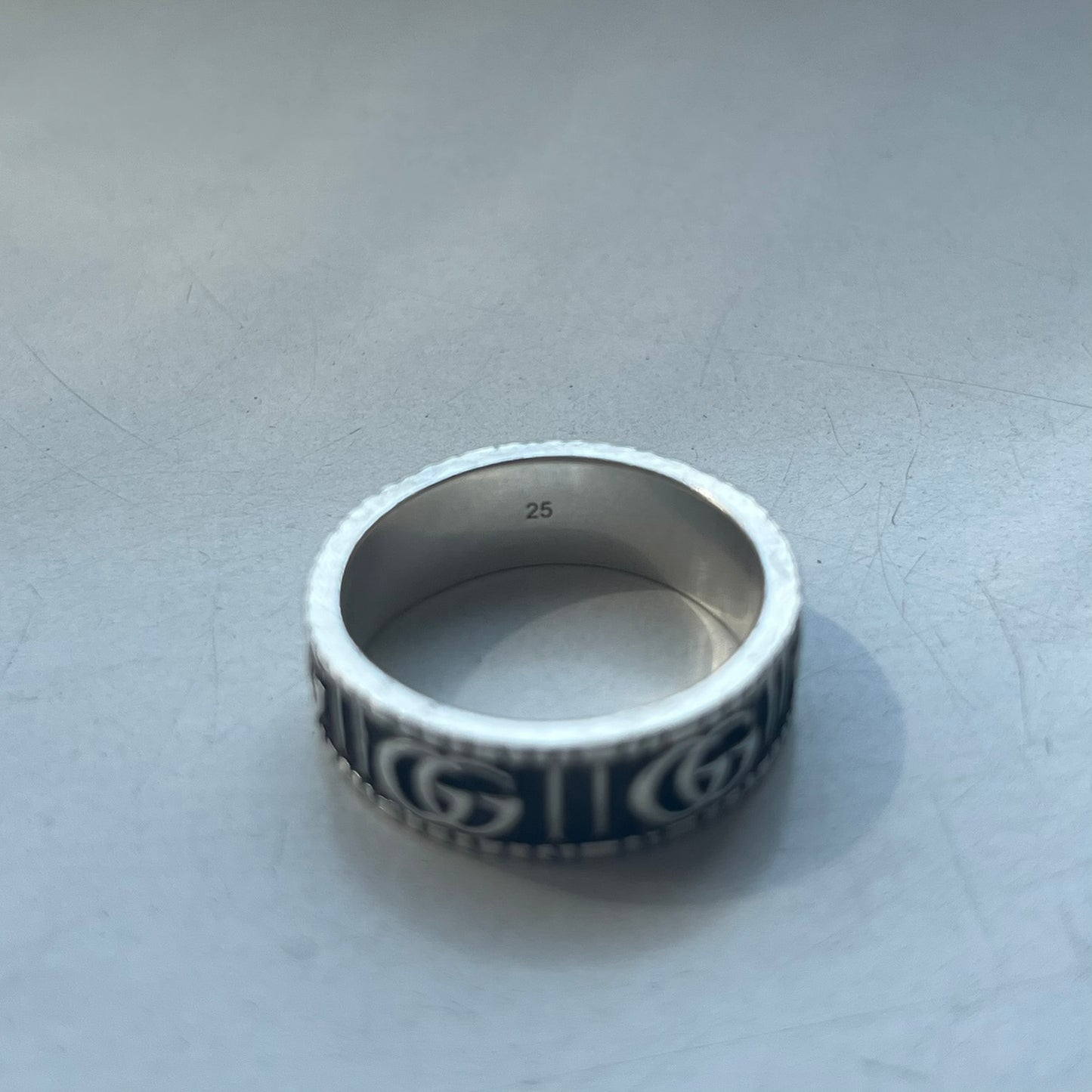Silver ring with intricate design on a light gray background