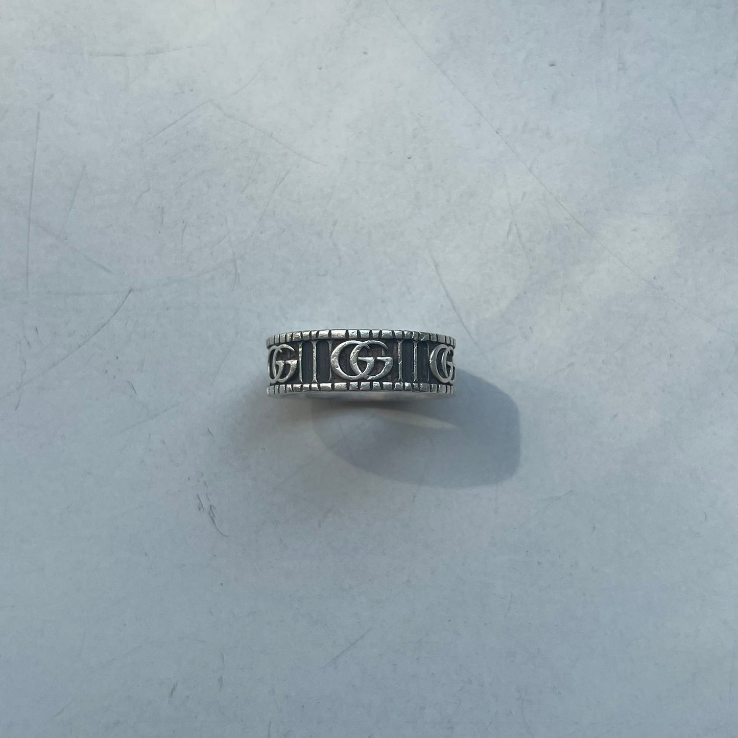 Silver ring with engraved design on a textured gray surface