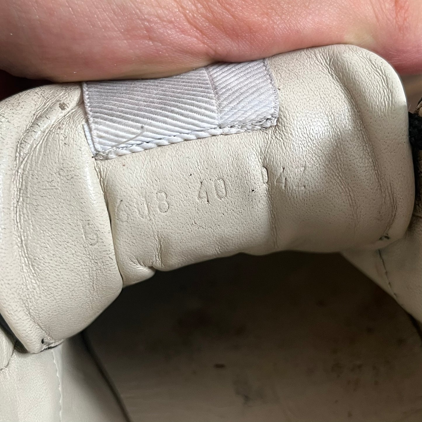 Close-up of a beige leather shoe with visible stitching and brand name.