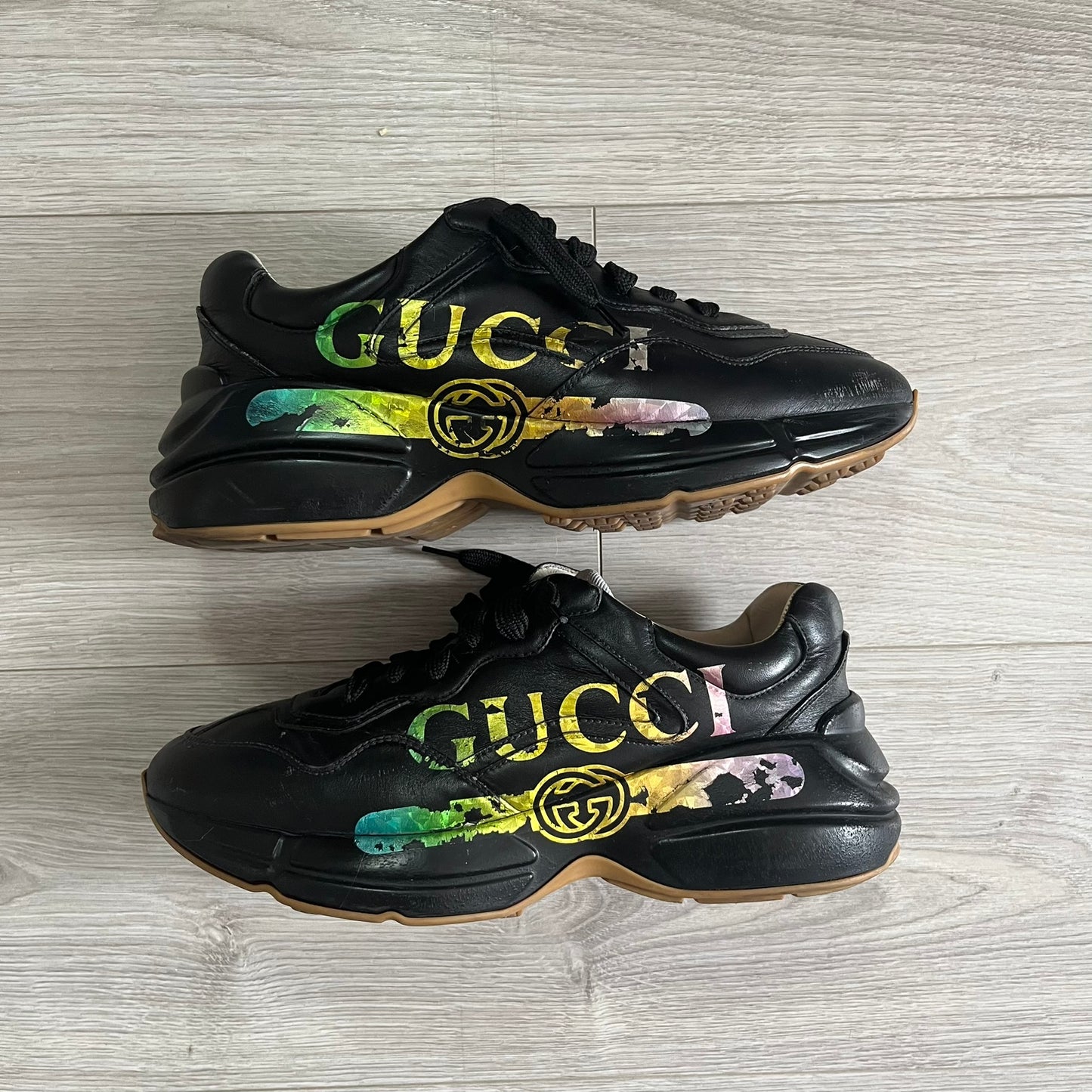 Black Gucci sneakers with colorful design on a wooden floor