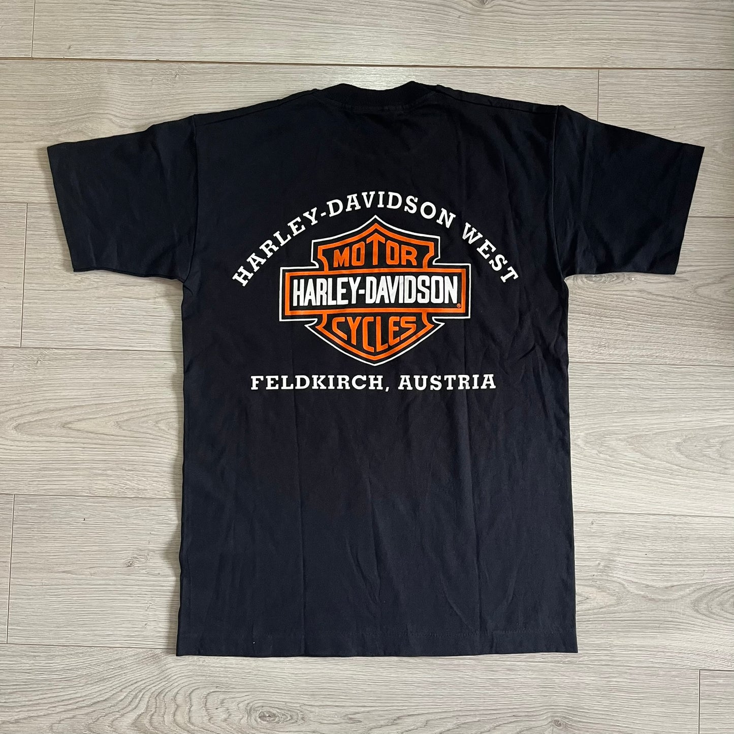 Black t-shirt with Harley-Davidson logo and text on a wooden surface