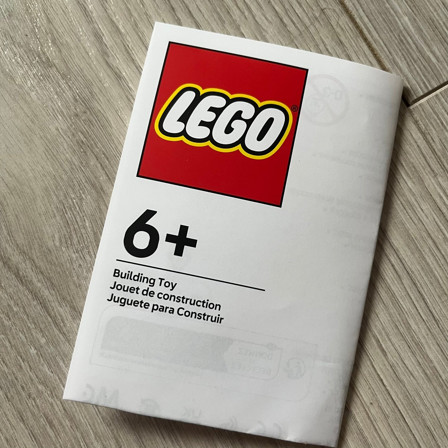 LEGO building toy packaging with age recommendation on a wooden surface