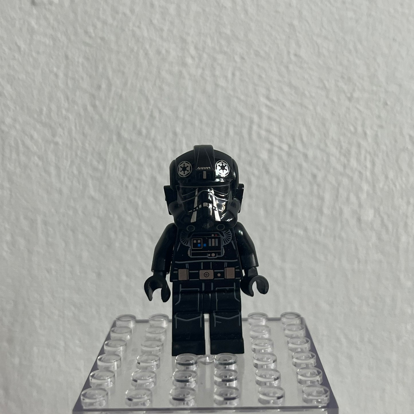 Black LEGO minifigure on a clear baseplate against a white background