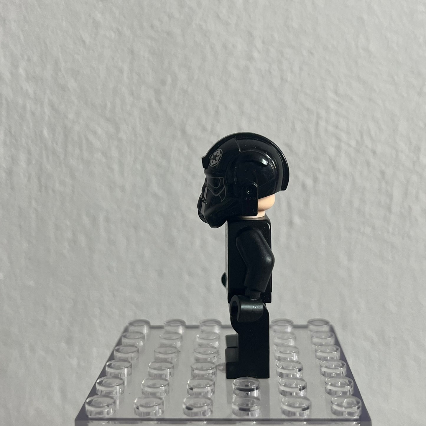 Black LEGO figure on a clear baseplate against a gray background