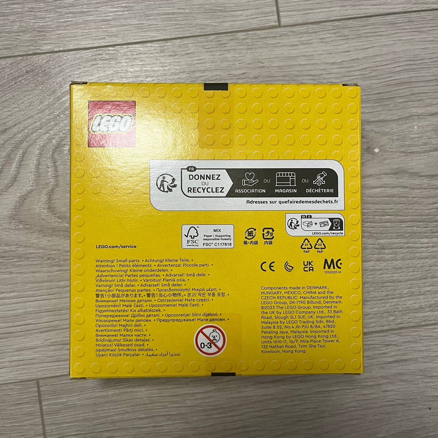 Yellow LEGO box with branding and recycling information on a wooden surface