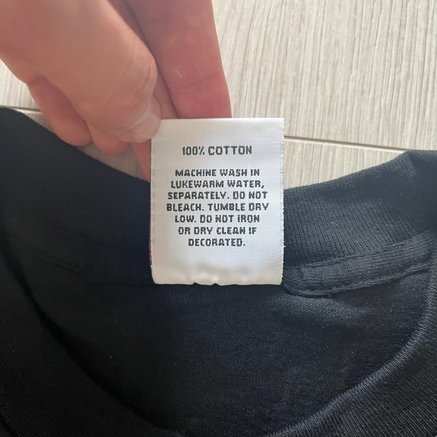 Clothing label on a black garment with washing instructions.