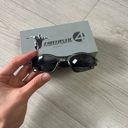 Sunglasses held by a hand with a 'Fantastic Four' box in the background