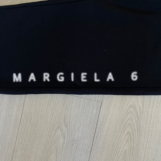 Black fabric with 'MARGIELA 6' text on a wooden surface