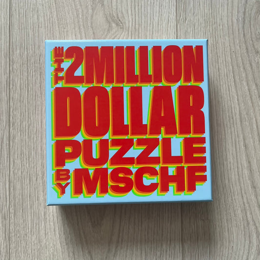 Box of 'The 2 Million Dollar Puzzle by MSCHF' on a wooden surface