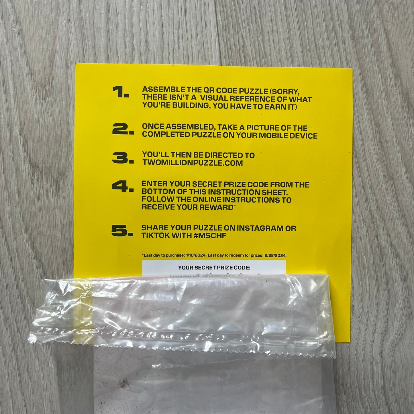 Yellow instruction sheet with text and a clear plastic bag on a wooden surface