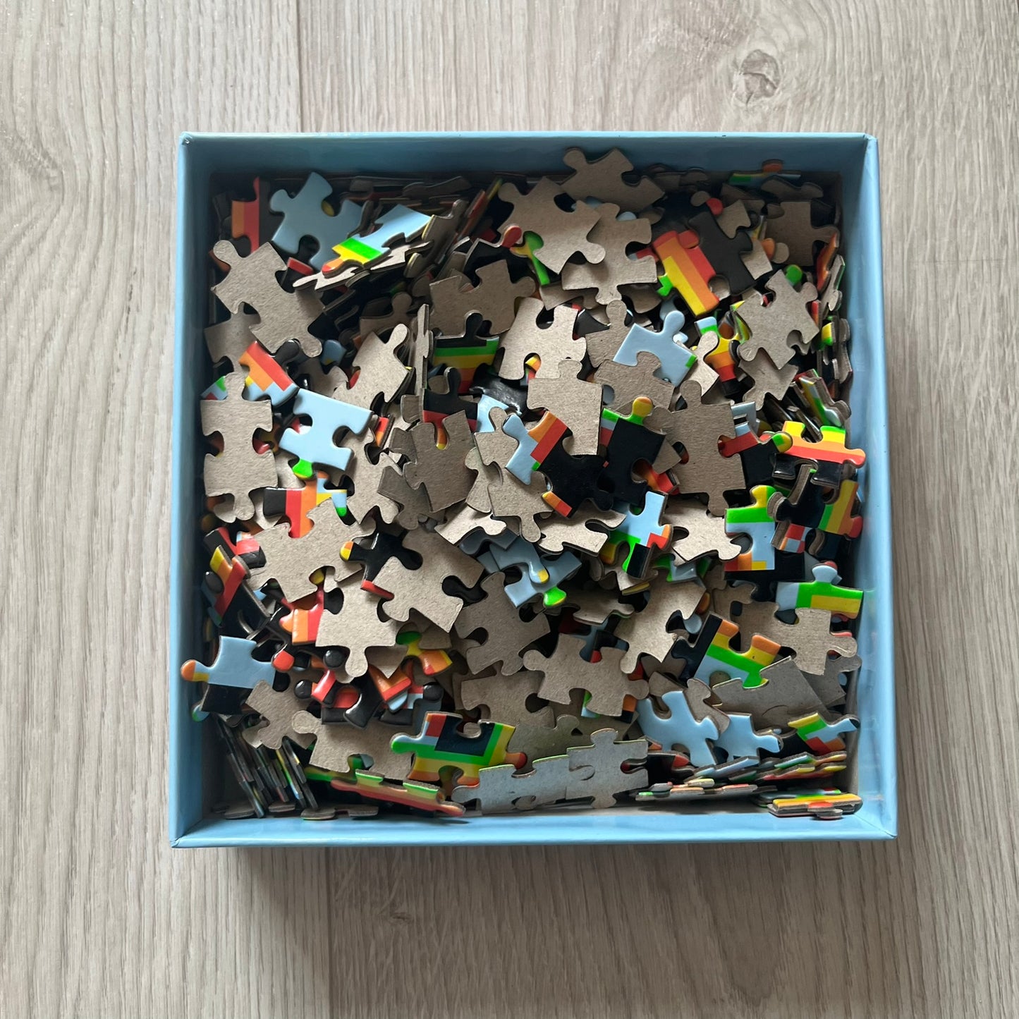 Box of puzzle pieces on a wooden surface