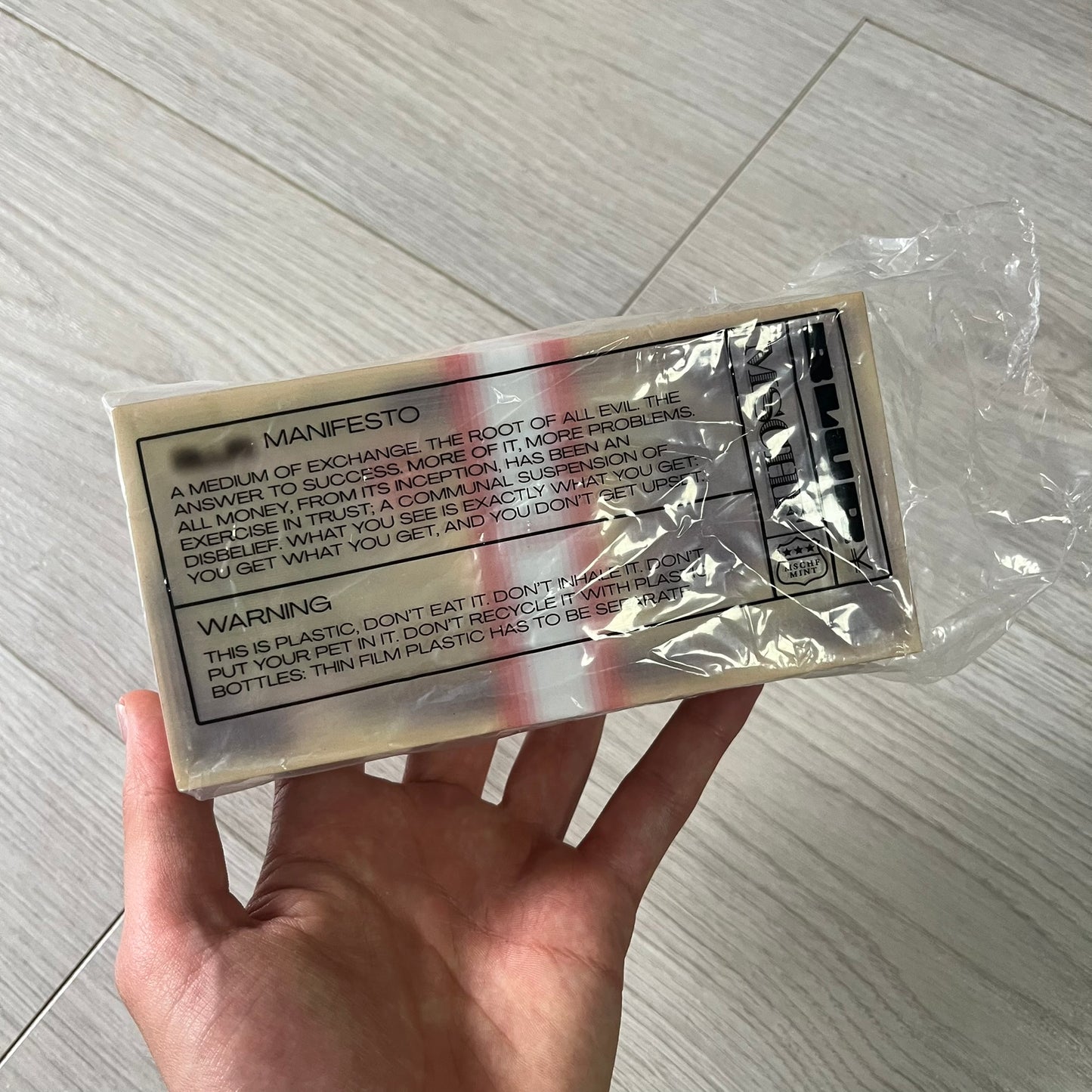 Hand holding a transparent plastic package with text on a light wooden surface