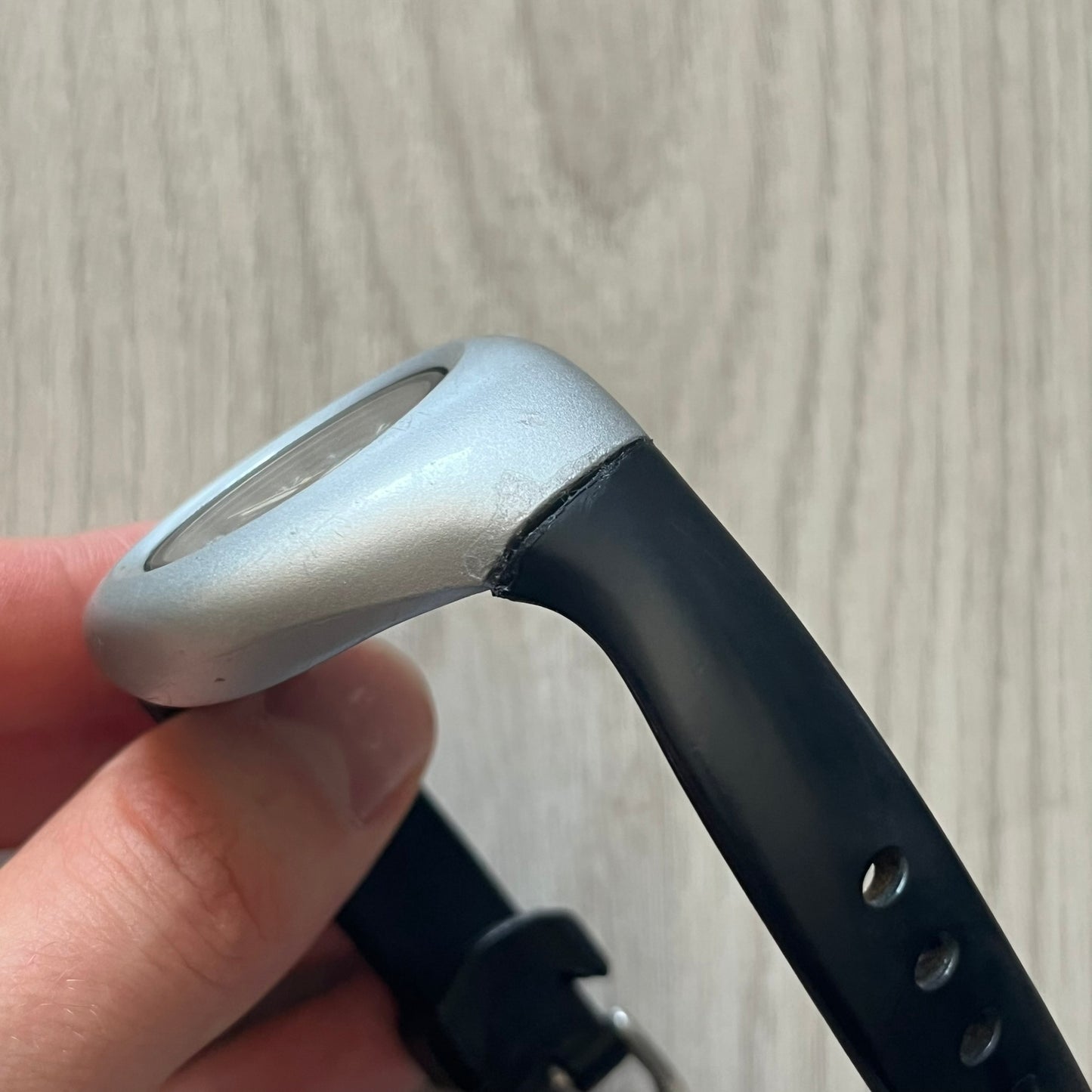 Golf club head held by a hand against a neutral background