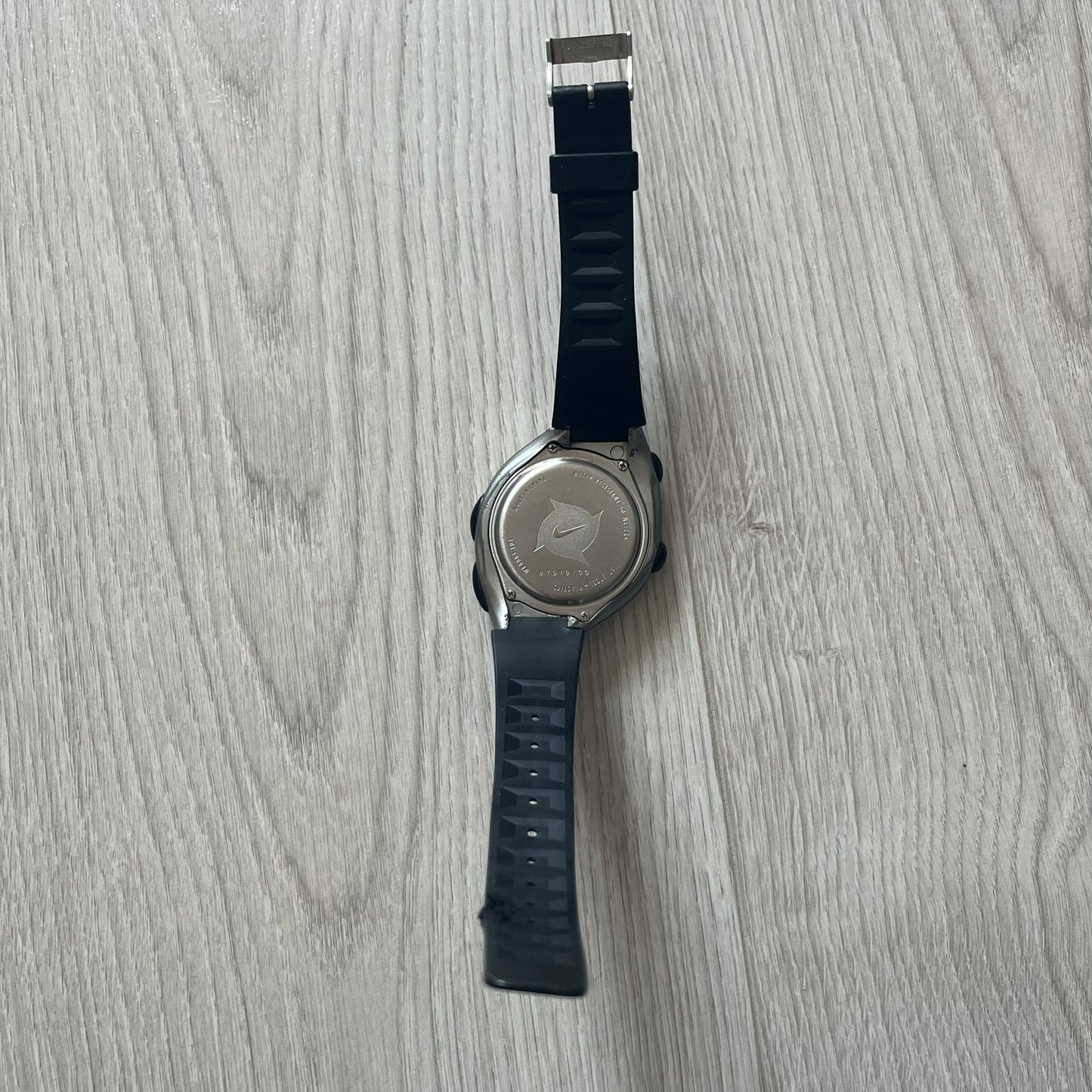Wristwatch with black strap on a light wooden surface