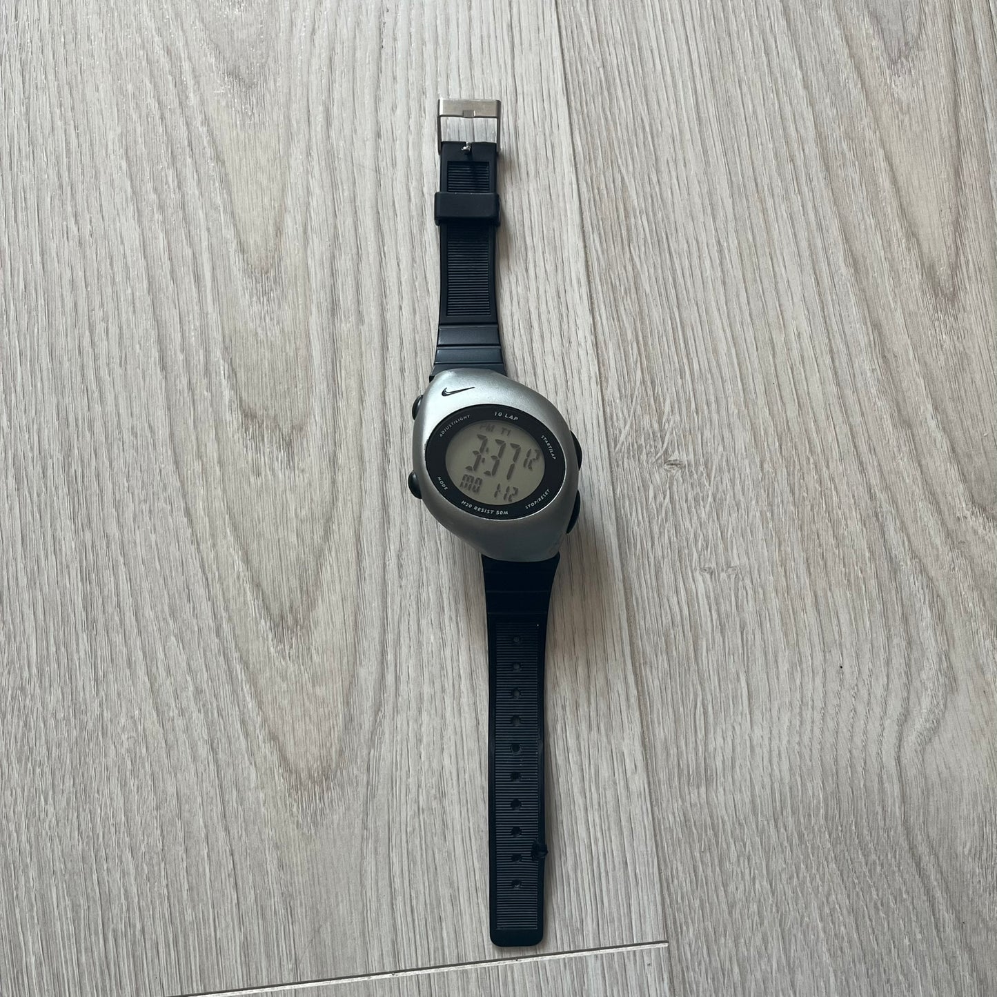 Digital watch with black strap on a light wooden surface