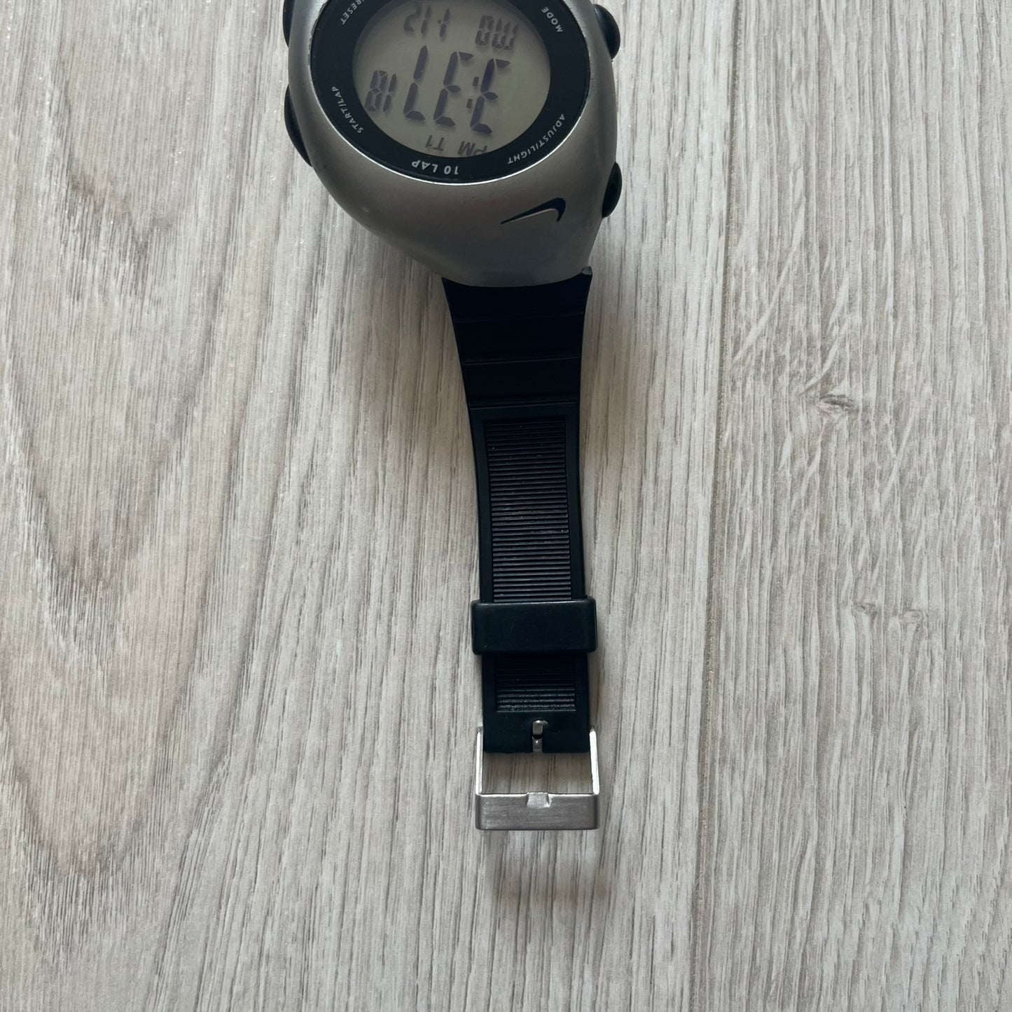 Digital watch with black strap on a wooden surface