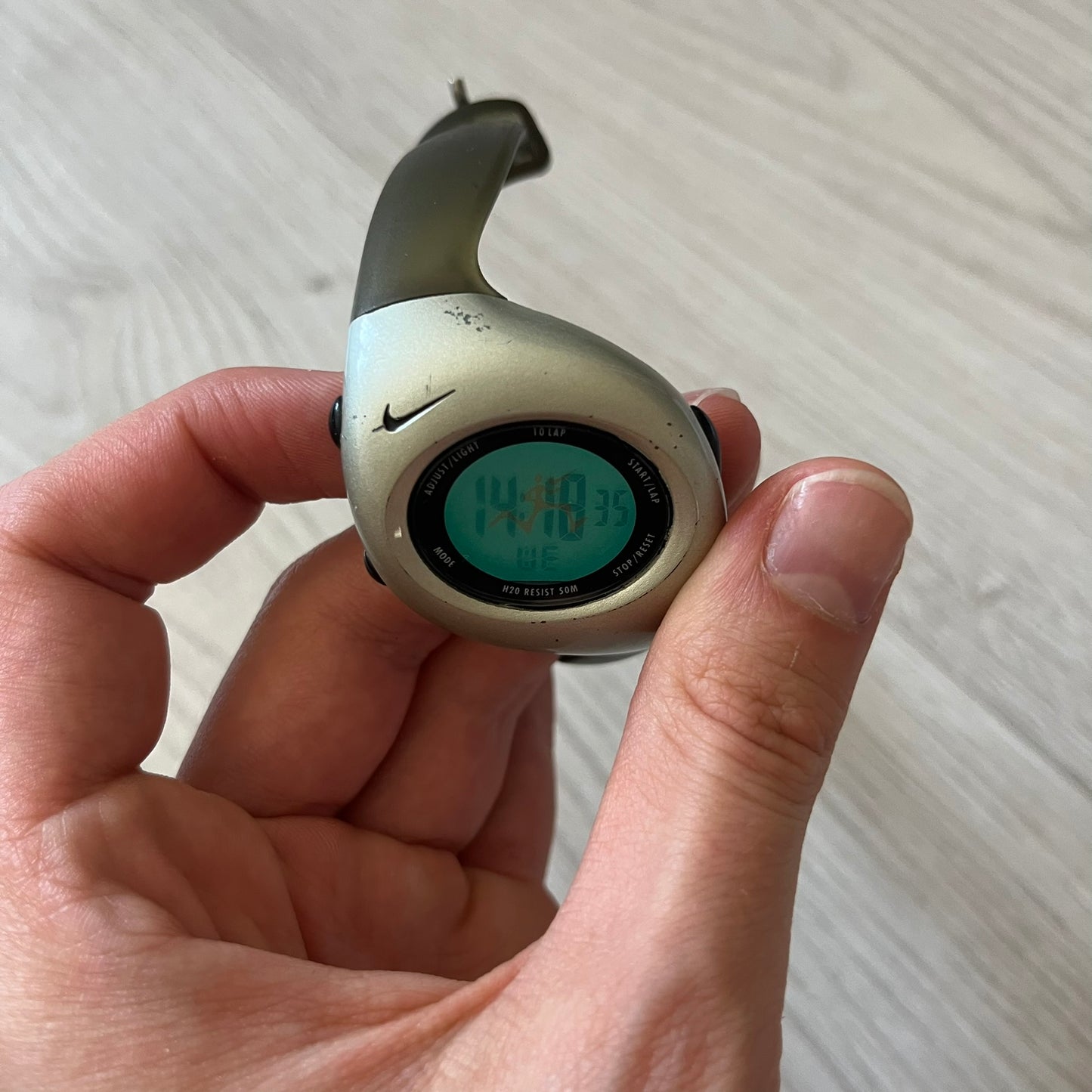 Hand holding a digital device with Nike logo on a light background