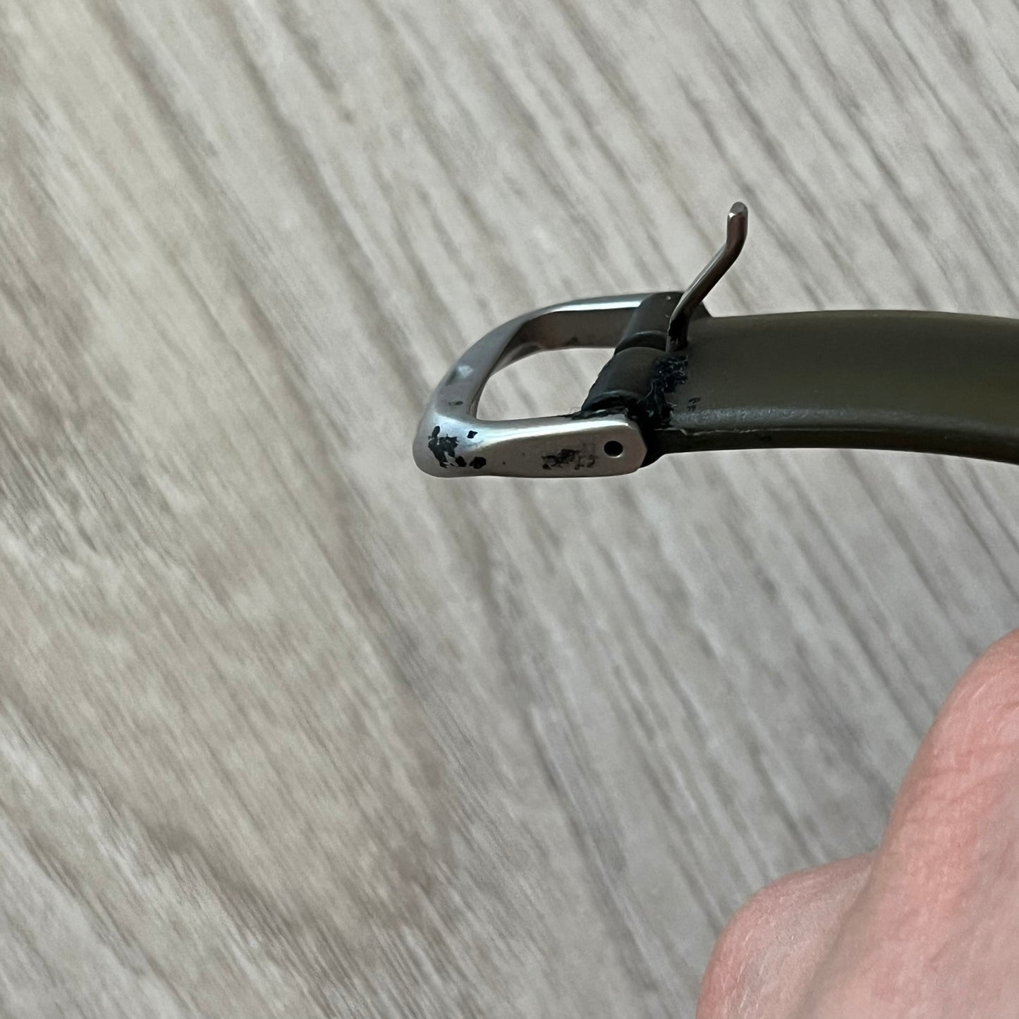 Close-up of a metal watch strap end on a wooden surface