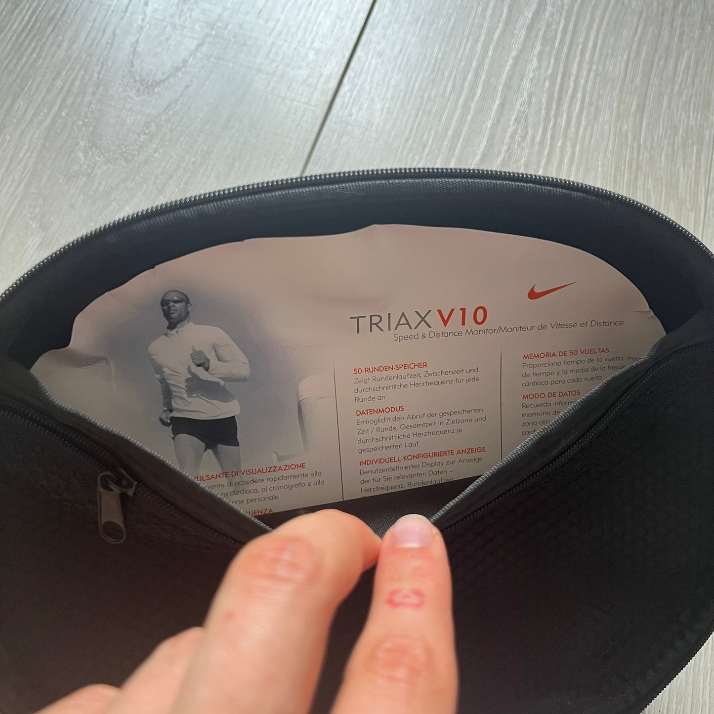 Person opening a black bag with 'TRIAX V10' and Nike branding visible.