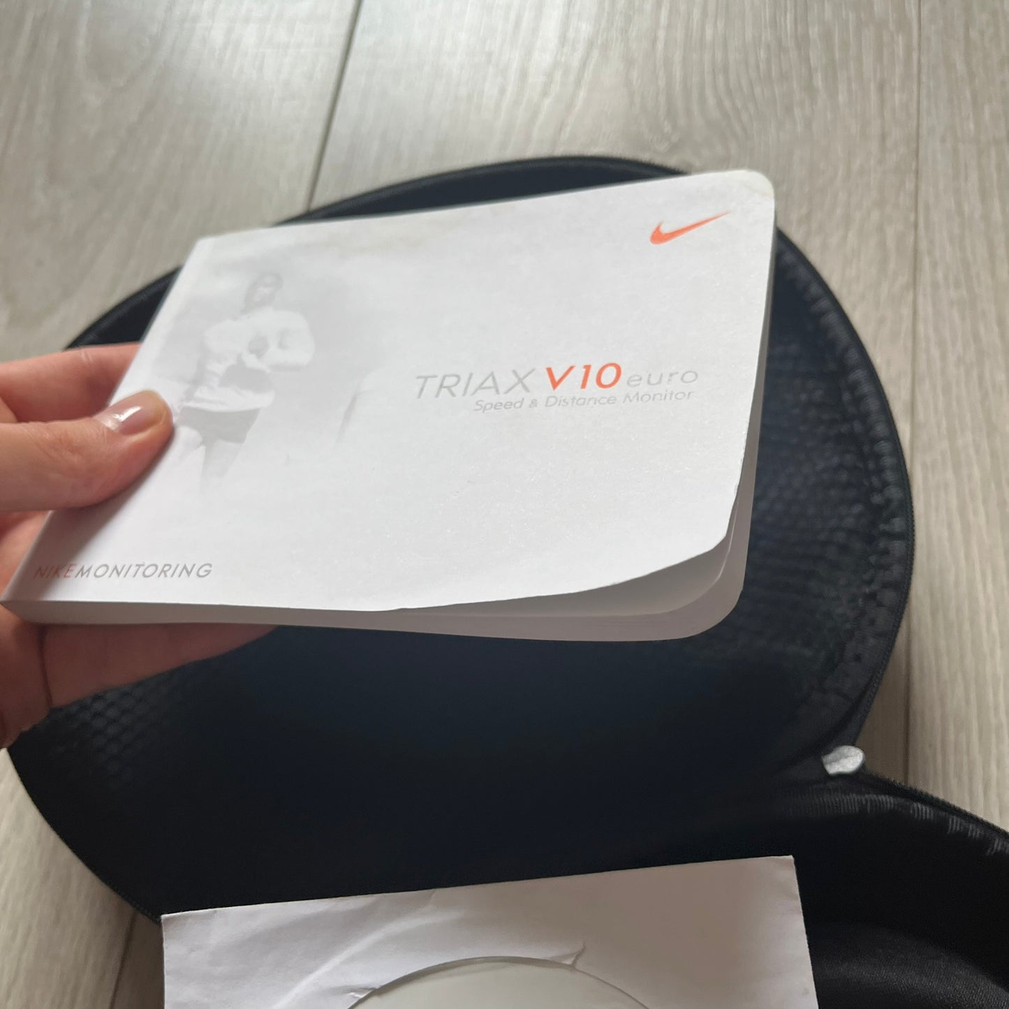 Person holding a white device labeled 'TRIAAX V10' on a black surface.
