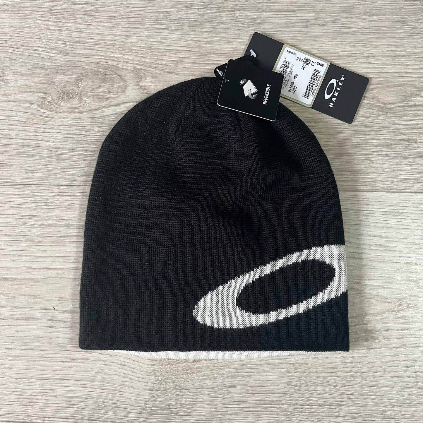 Black beanie with a white logo on a wooden surface