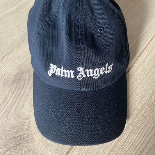 Navy blue cap with 'Palm Angels' logo on a wooden surface