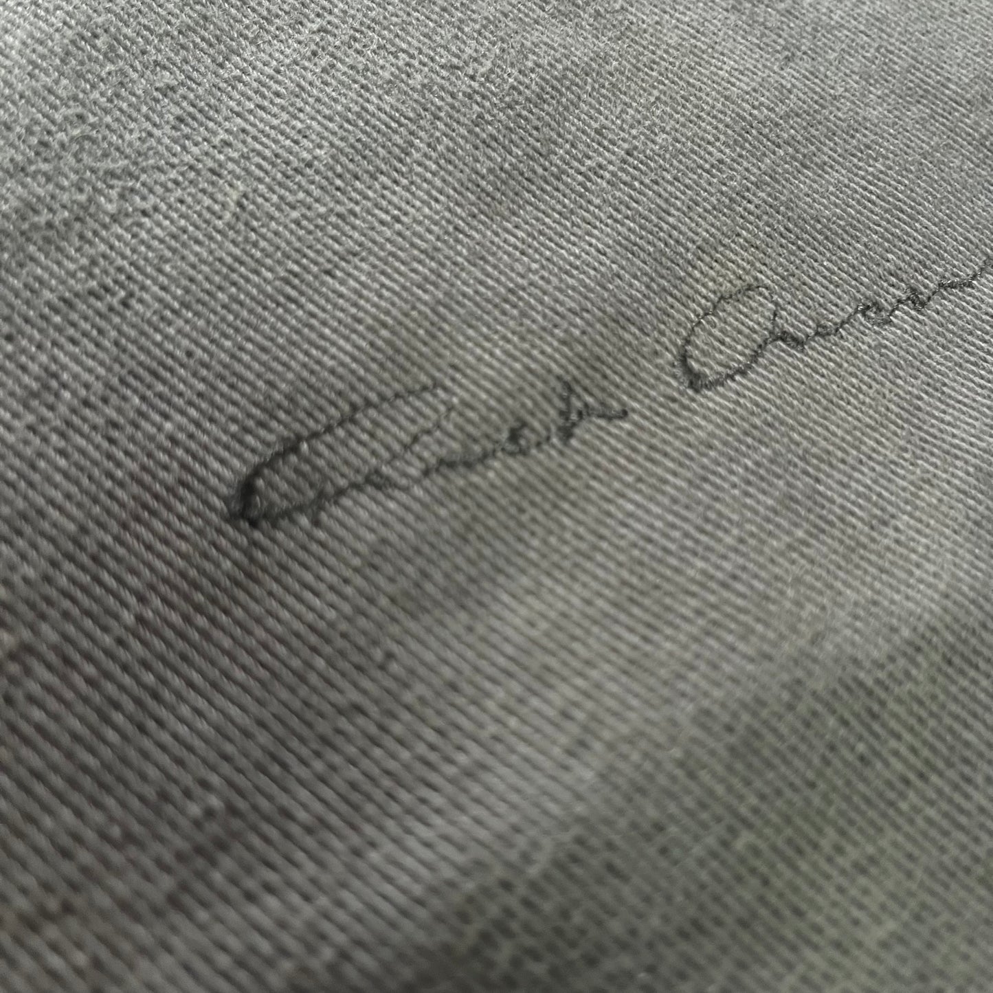 Signature on a textured gray fabric surface