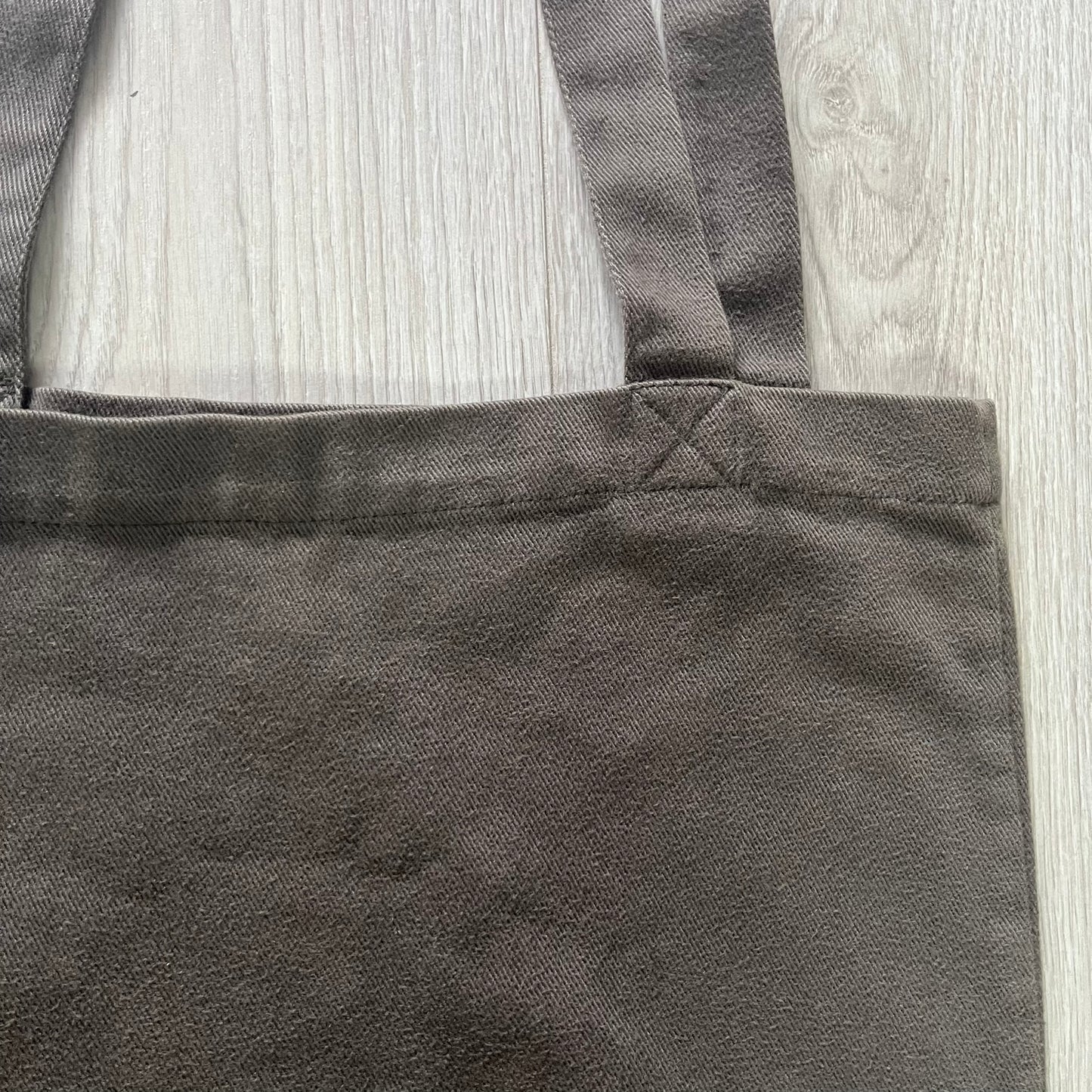 Close-up of a dark gray apron on a light wooden surface