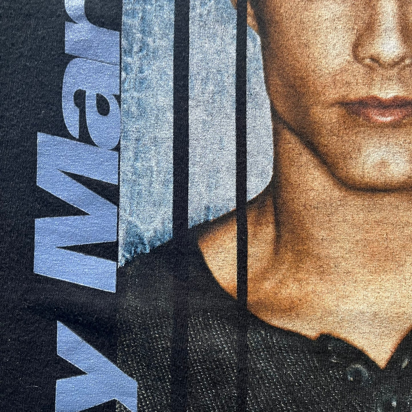 Close-up of a person wearing a black garment with branding on a blue background