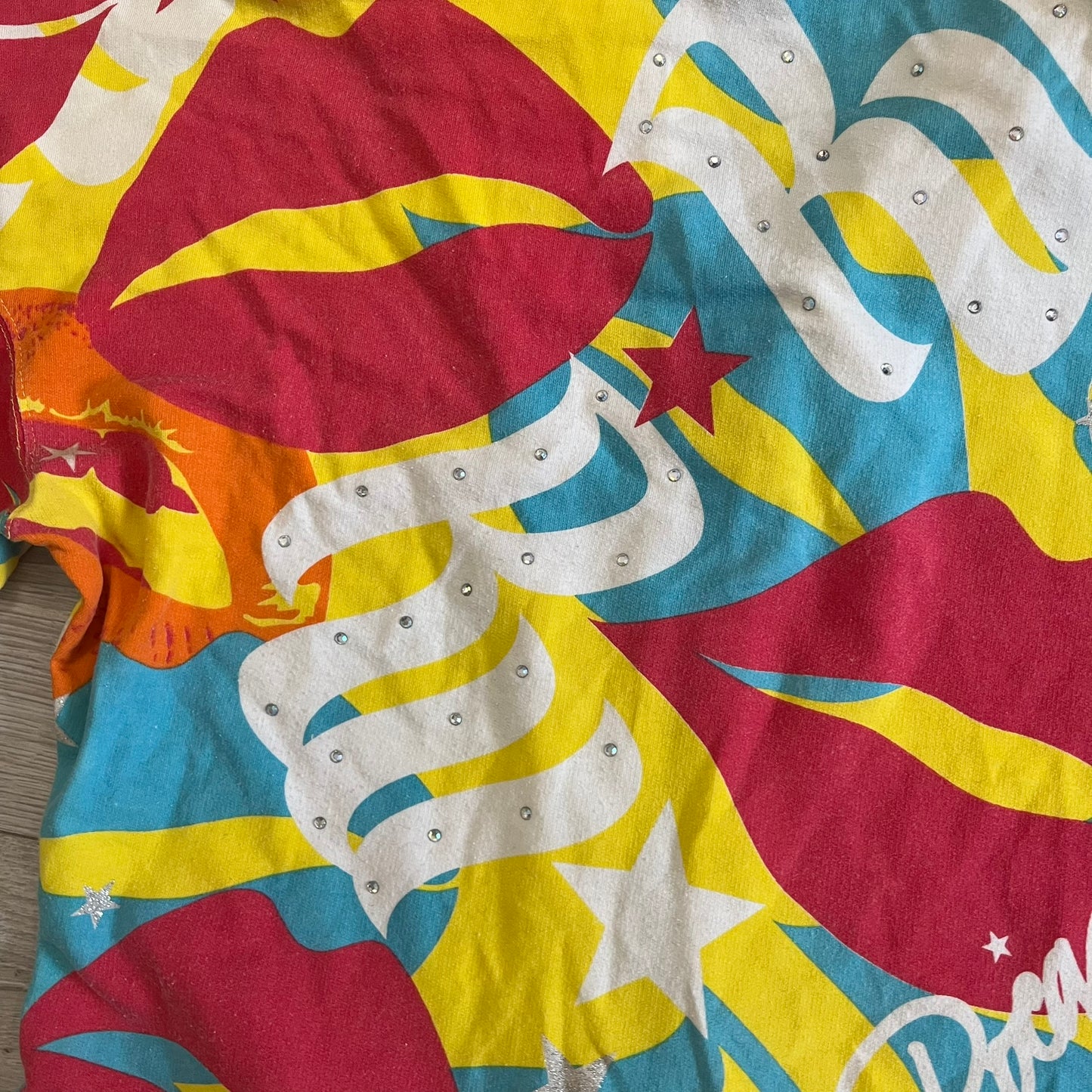 Colorful tie-dye shirt with star and moon patterns on a wooden surface