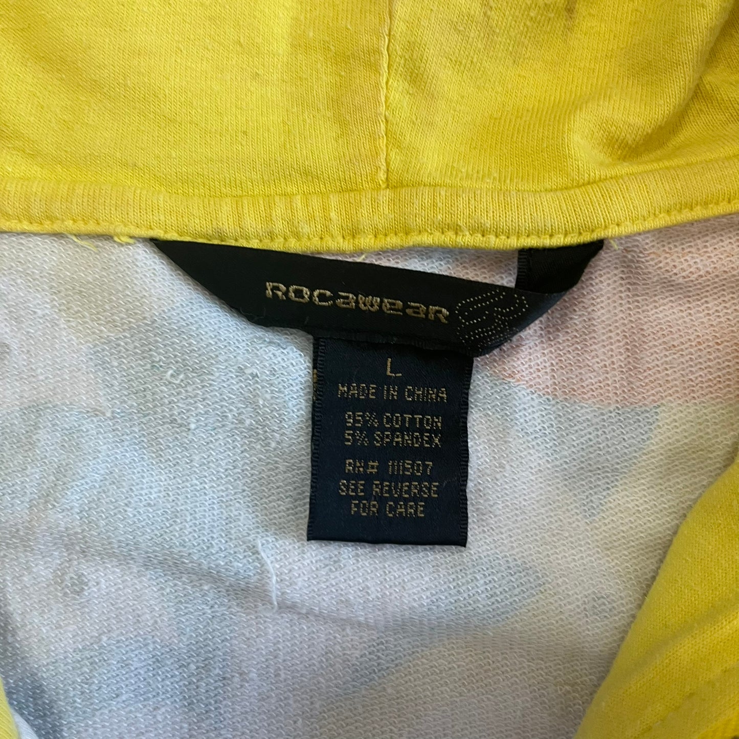 Close-up of a label on a yellow and white garment with 'Rocawear' branding.