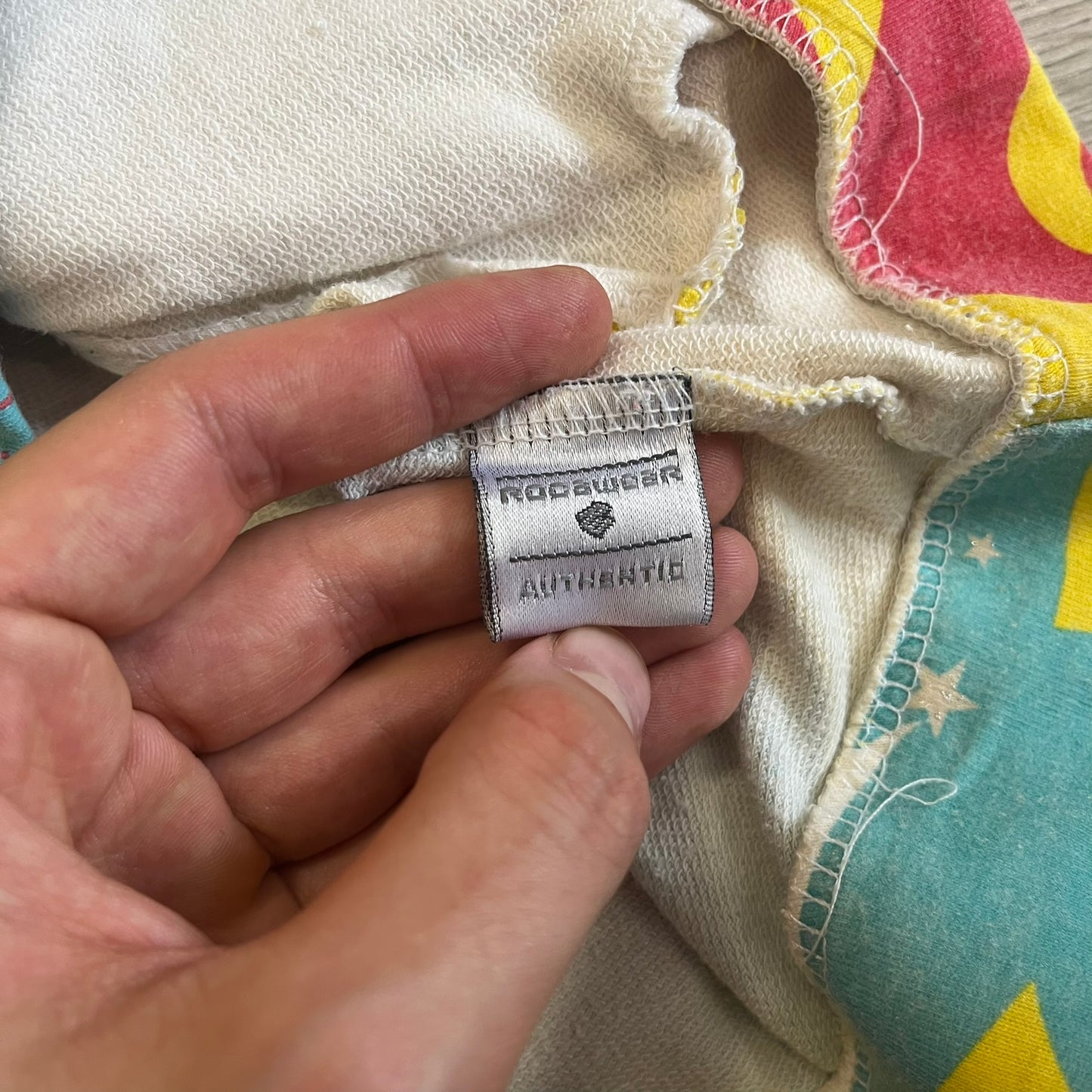 Hand holding a label on a piece of fabric with a colorful background