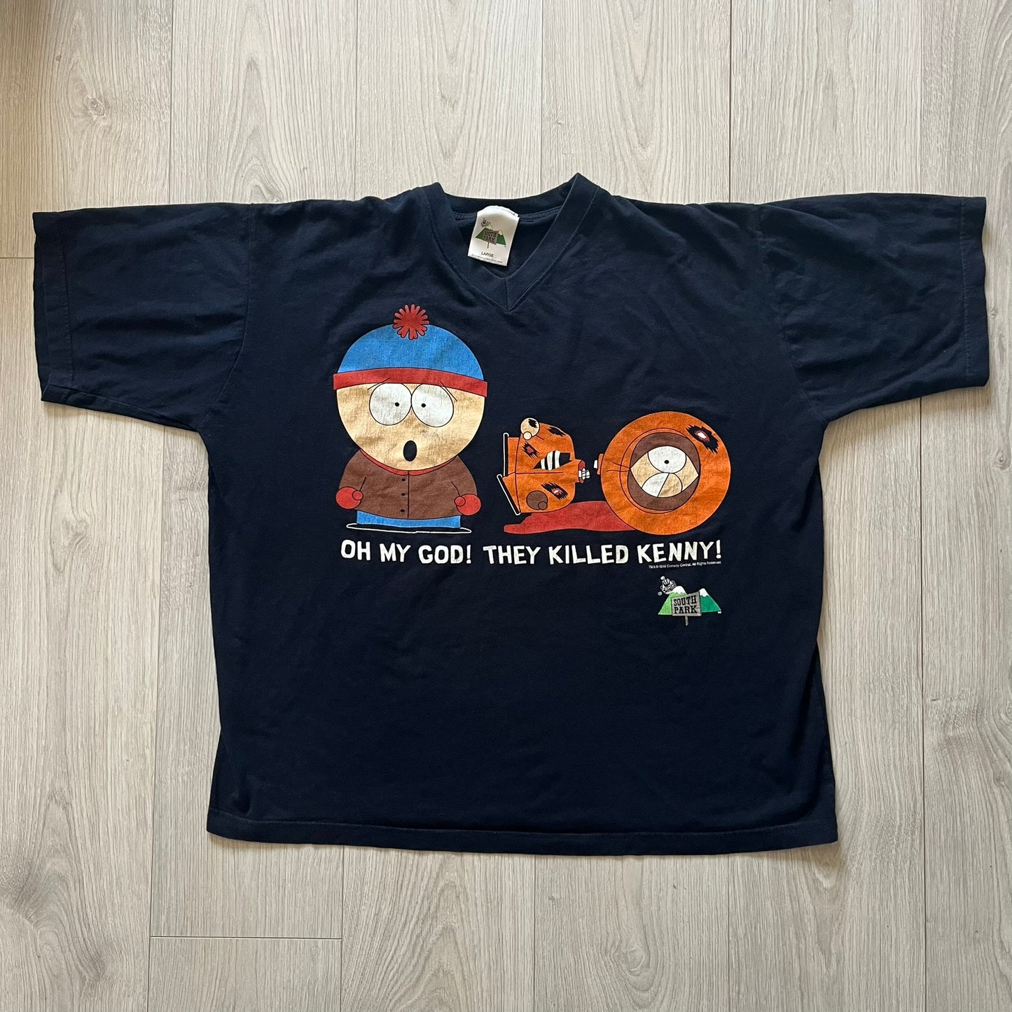 Black t-shirt with cartoon characters and text on a wooden surface