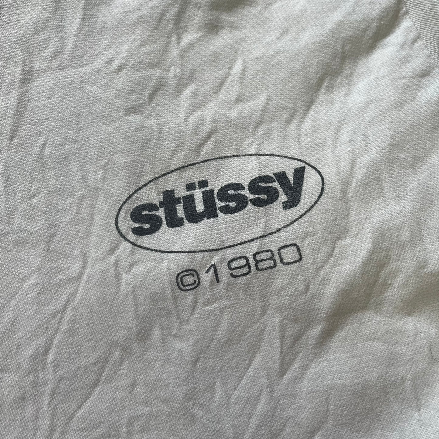 Close-up of a gray fabric with 'stussy' logo and '01980' text.