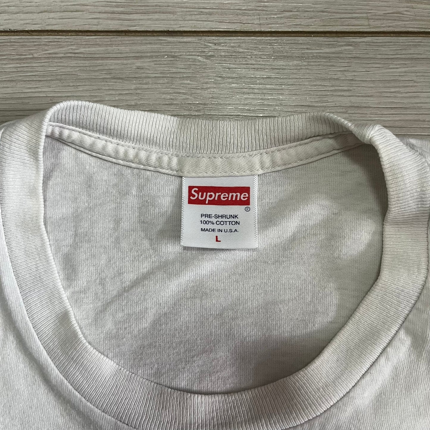 Gray sweatshirt with a Supreme label on a wooden surface