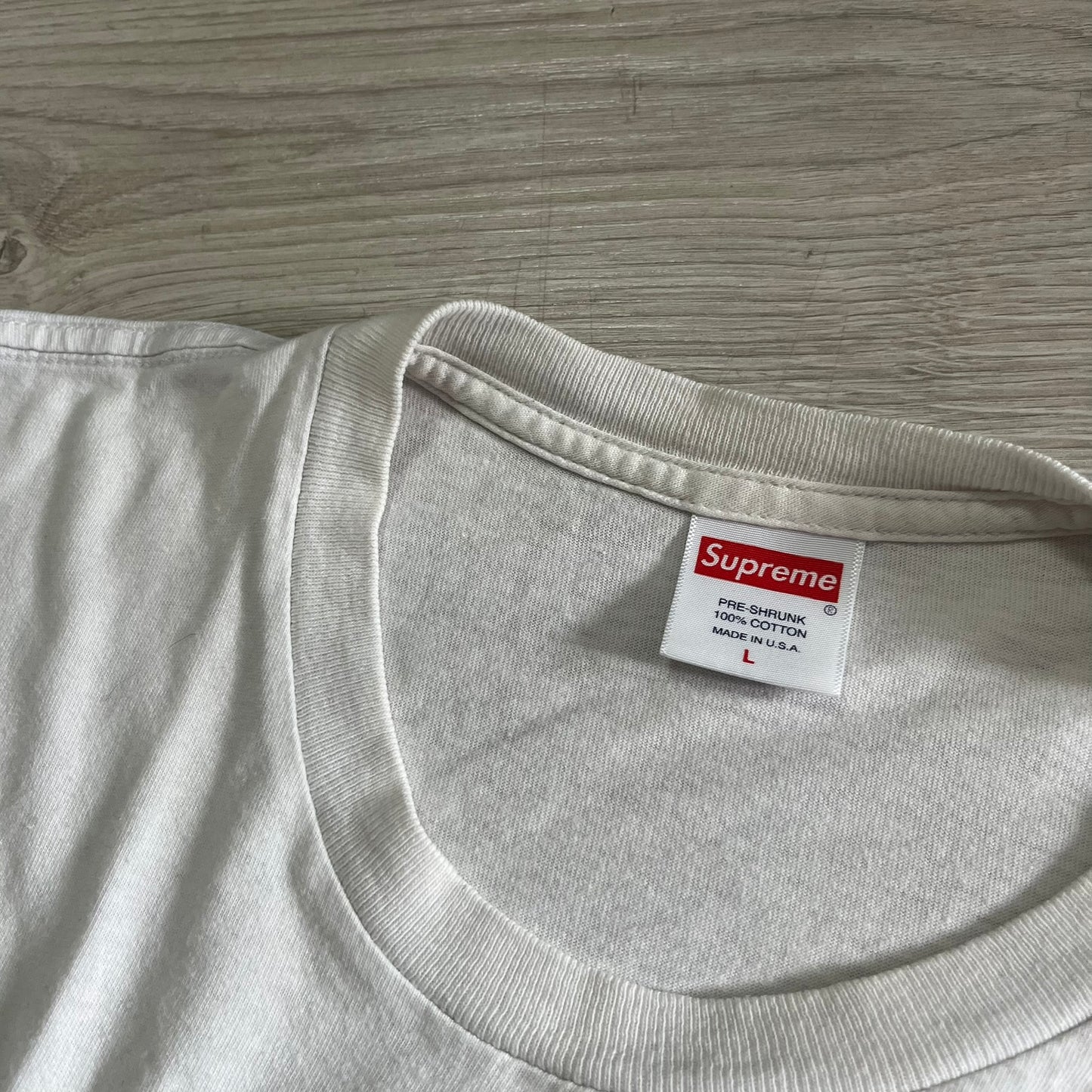 Gray t-shirt with a Supreme label on a wooden surface