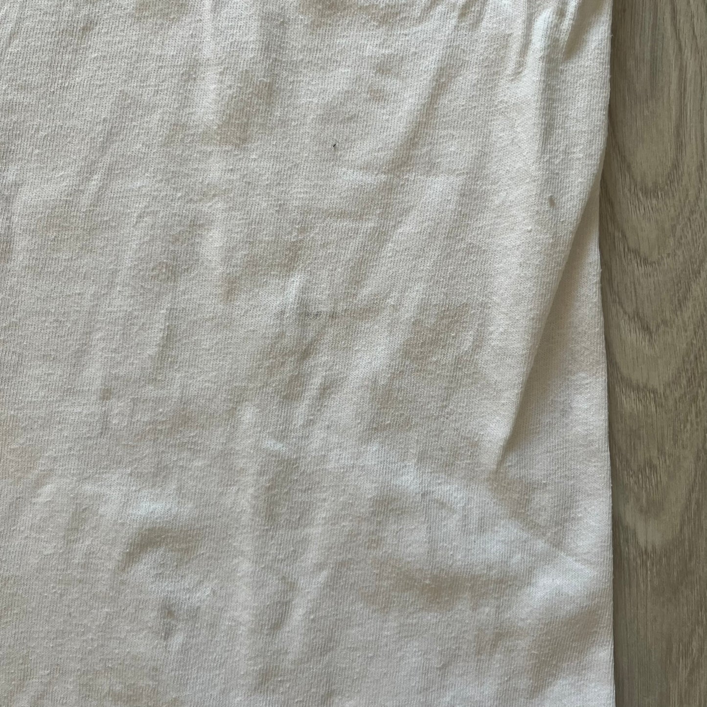 Close-up of a light gray fabric with a wooden surface background
