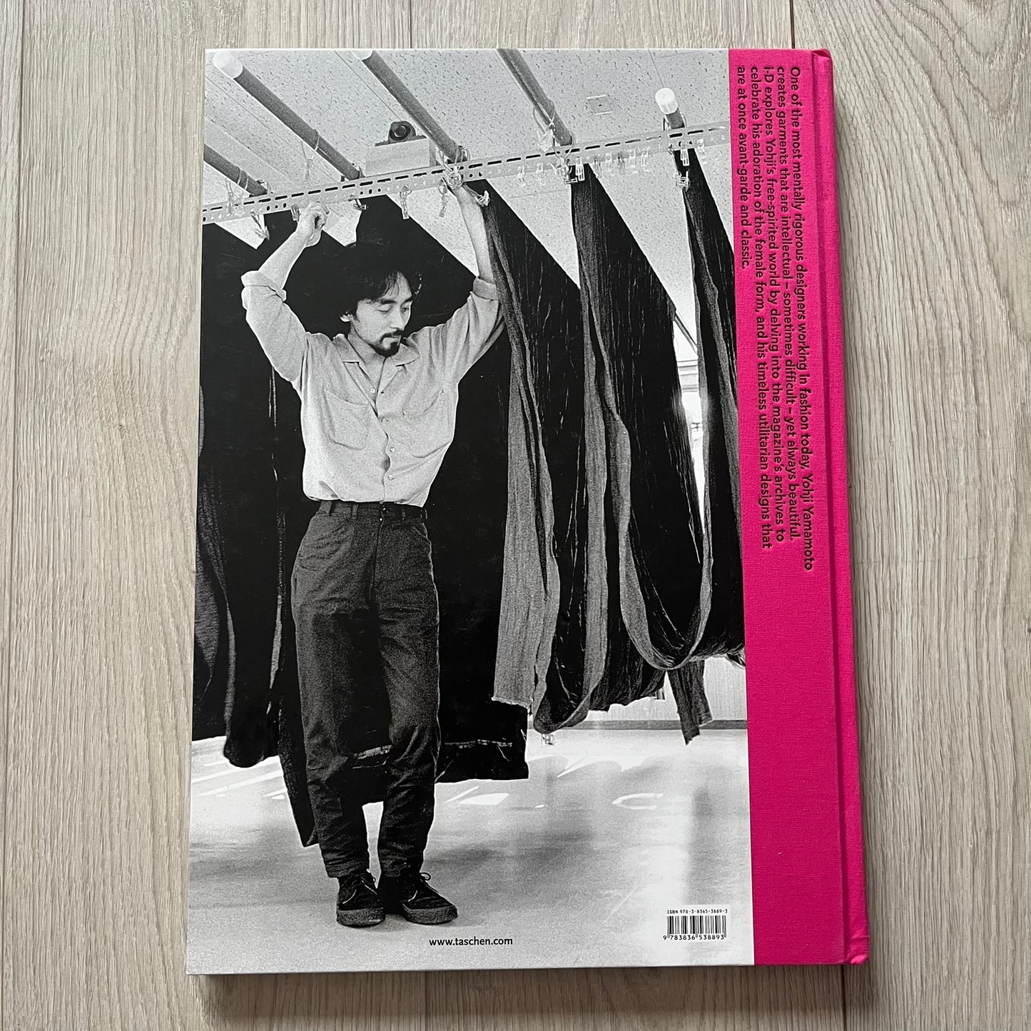 Book cover with a black and white photo of a person hanging clothes on a rack, pink spine.
