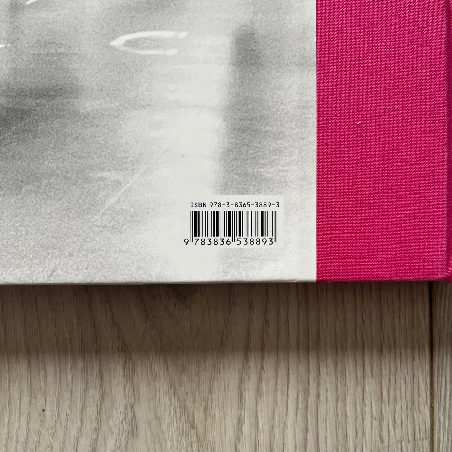 Close-up of a book with a pink cover and a visible ISBN label on a wooden surface.