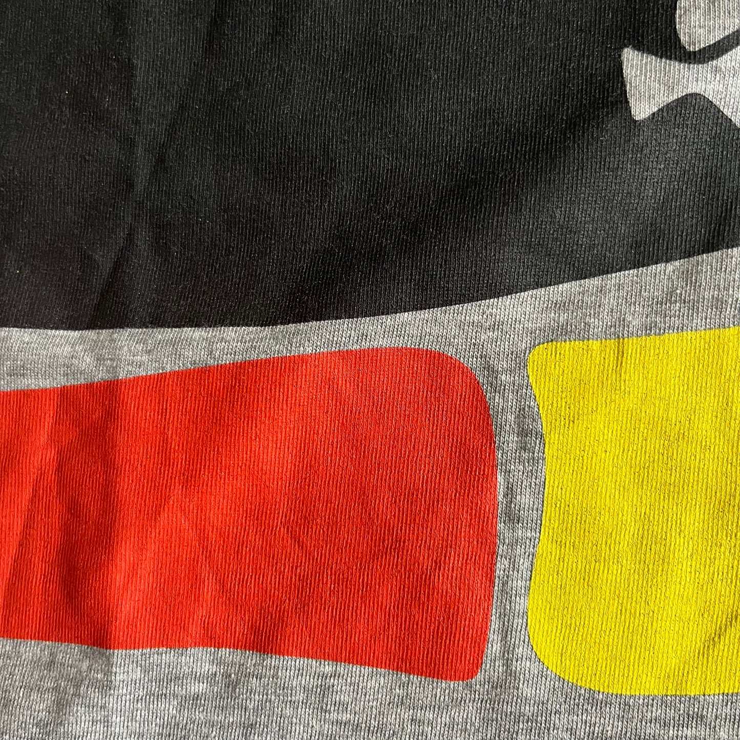 Close-up of a gray shirt with red and yellow geometric shapes
