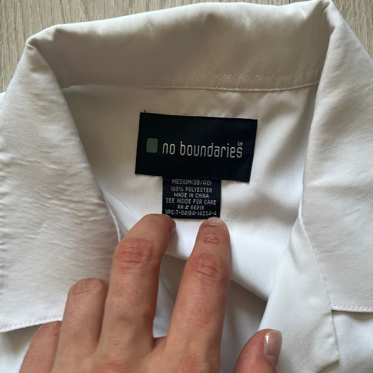 Hand holding a clothing tag on a white garment